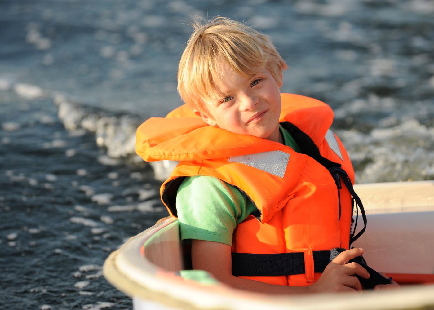 Kind in Boot mit signalfarbener Weste